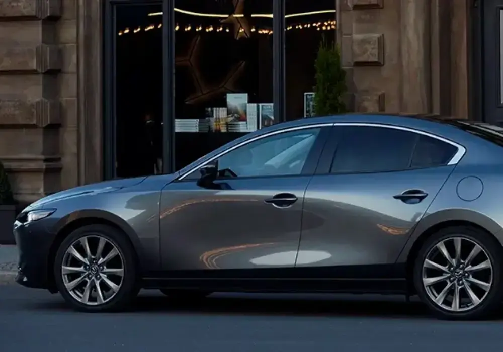 Mazda 3 sedán gris oscuro estacionado en la calle